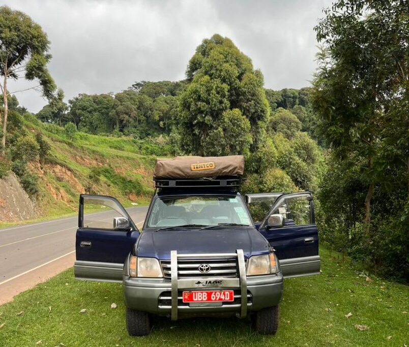 A rental SUV overlooking Rwanda’s beautiful lakes and green mountains, illustrating the freedom of exploring Rwanda by car.